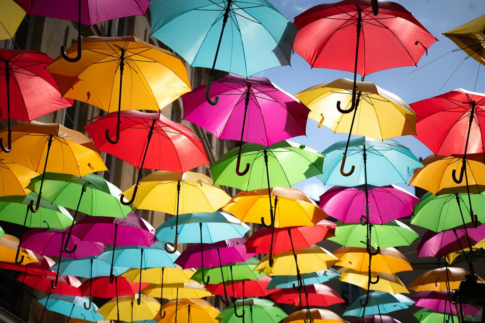 Viele bunte Regenschirme schweben über einer Straße